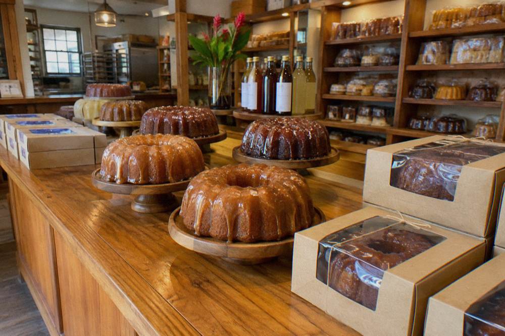 Rum tasting glasses and a slice of rum cake on a wooden bar counter in warm light