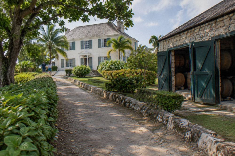 Historic Georgian-style estate building with white columns surrounded by tropical gardens