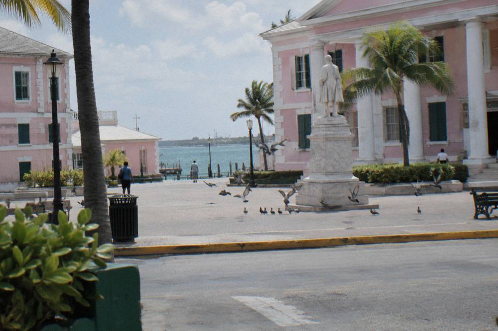 Pastel colonial government buildings arranged around a small square with a statue