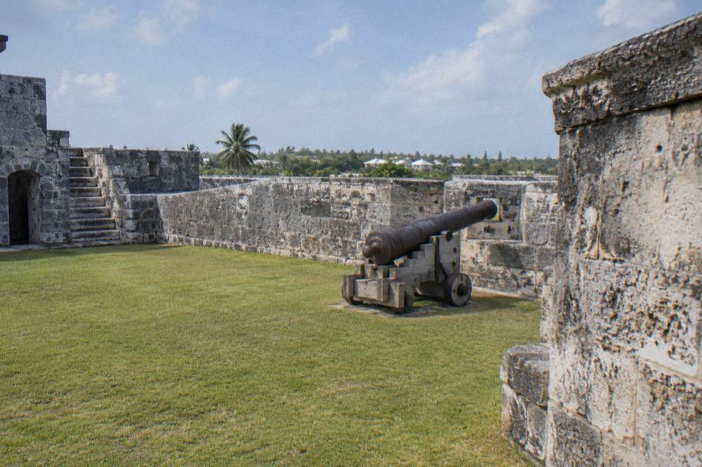 Stone fort walls on a hill overlooking a harbor with cruise ships at dock