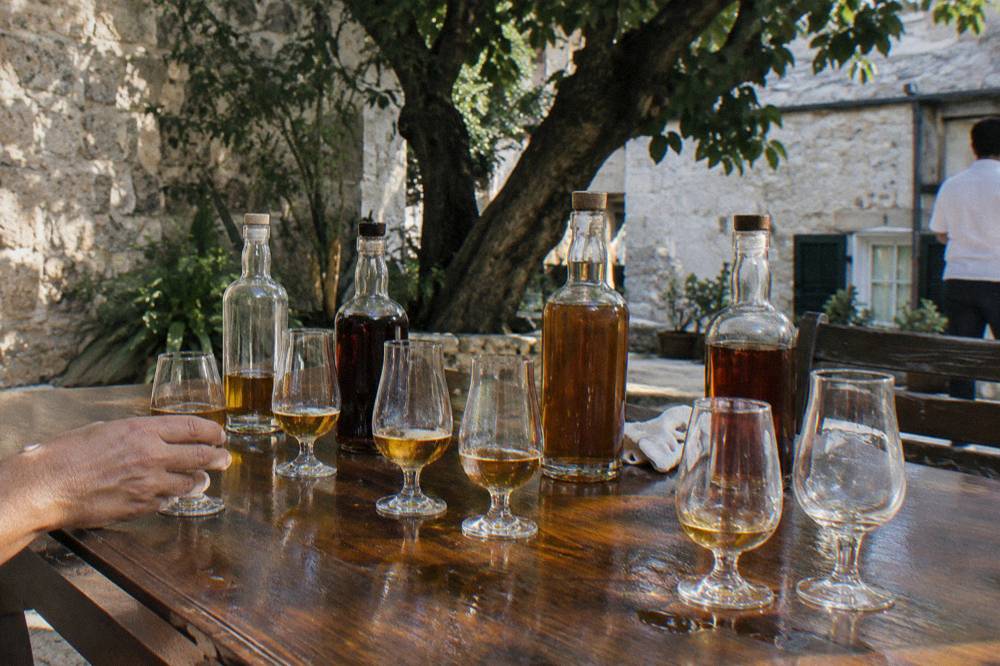 A row of labeled rum bottles on a tasting bar with a wooden counter