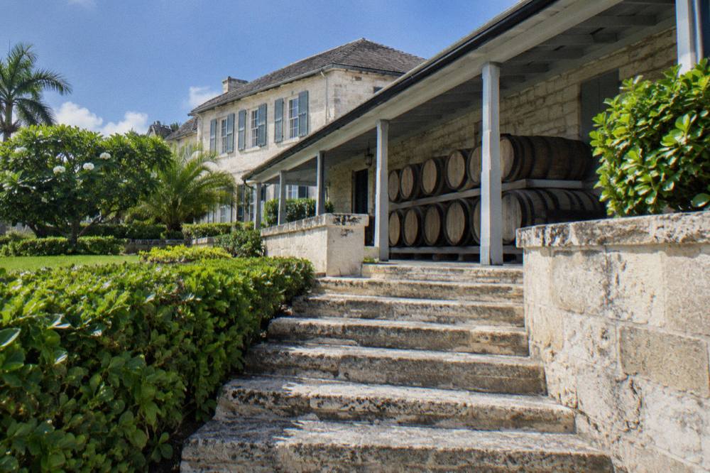 Colonial-era stone distillery building surrounded by tropical gardens and palm trees