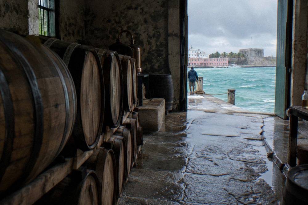A line of white oak rum barrels inside a dimly lit storehouse