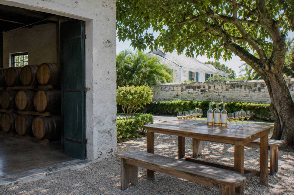 White oak aging barrels stacked in a stone-walled rum storehouse at a Nassau estate.