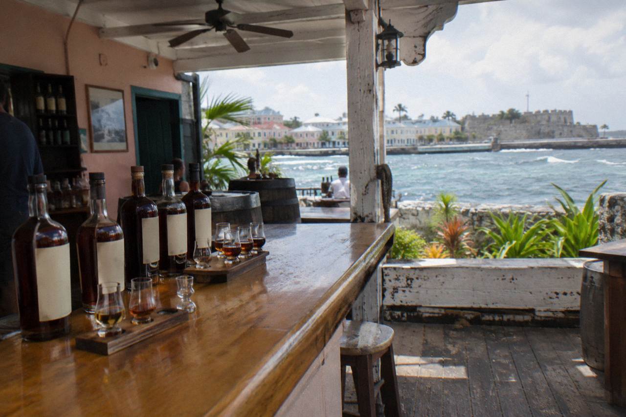 Rum bottles and tasting glasses arranged on a wooden bar counter in a historic distillery