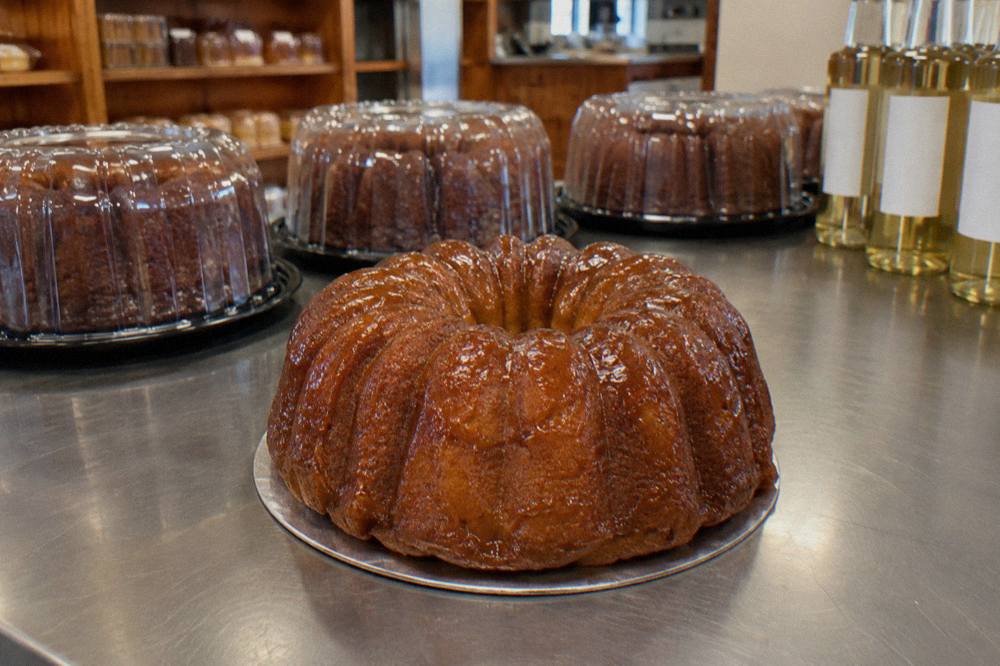 Whole bundt rum cake glazed and wrapped in clear packaging on a bakery counter