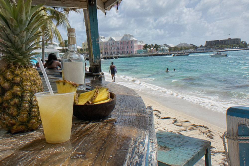 A pineapple and coconut rum cocktail beside fresh pineapple wedges on a weathered bar counter