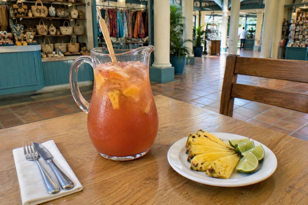 A rum punch garnished with nutmeg and a pineapple wedge on a sunny outdoor table