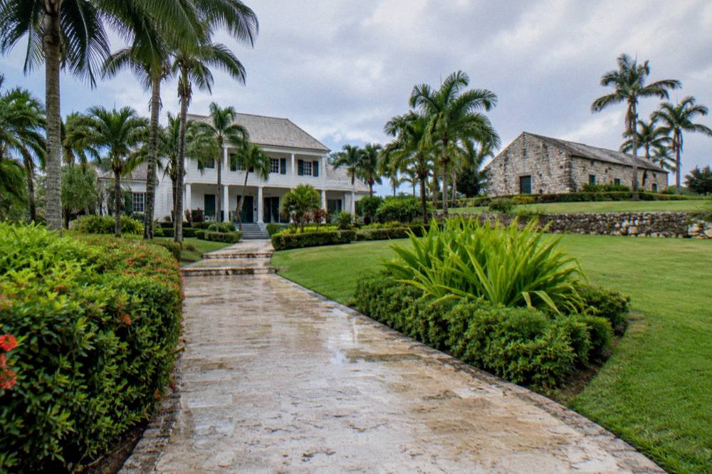 A hillside path leading to a historic estate building surrounded by palm trees