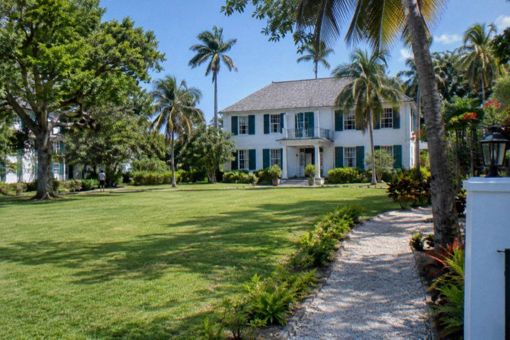 White colonial buildings and tropical gardens at a Nassau rum distillery estate