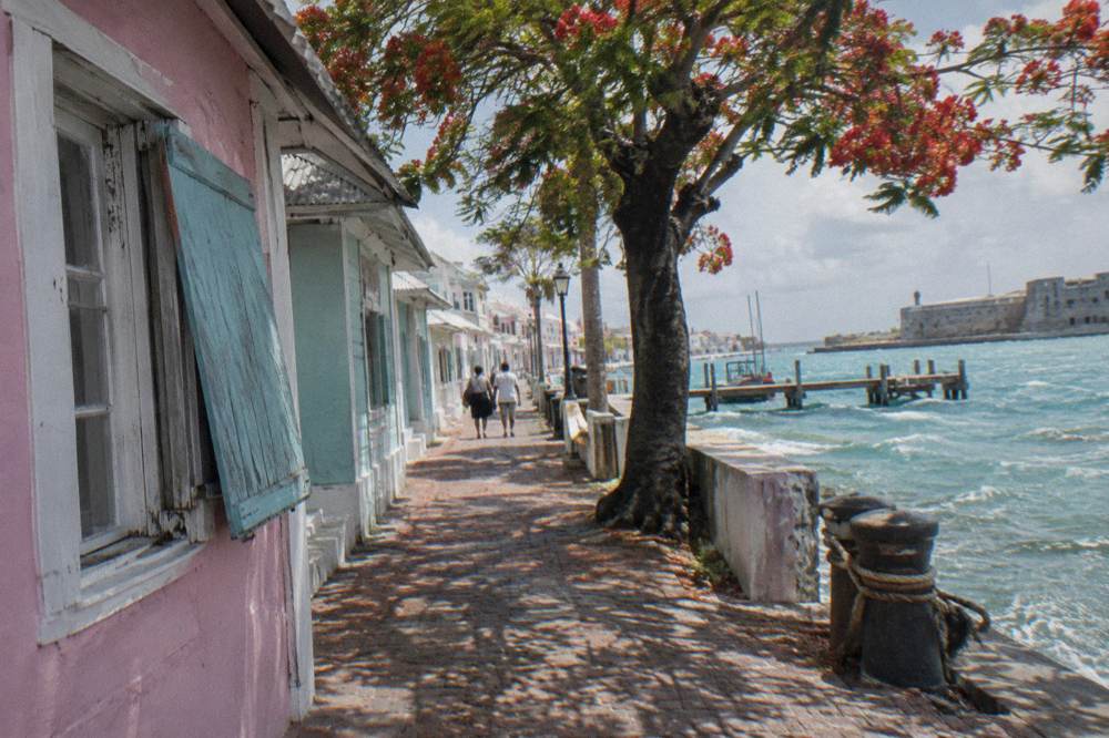 A narrow historic Nassau street with colorful low buildings and shade trees