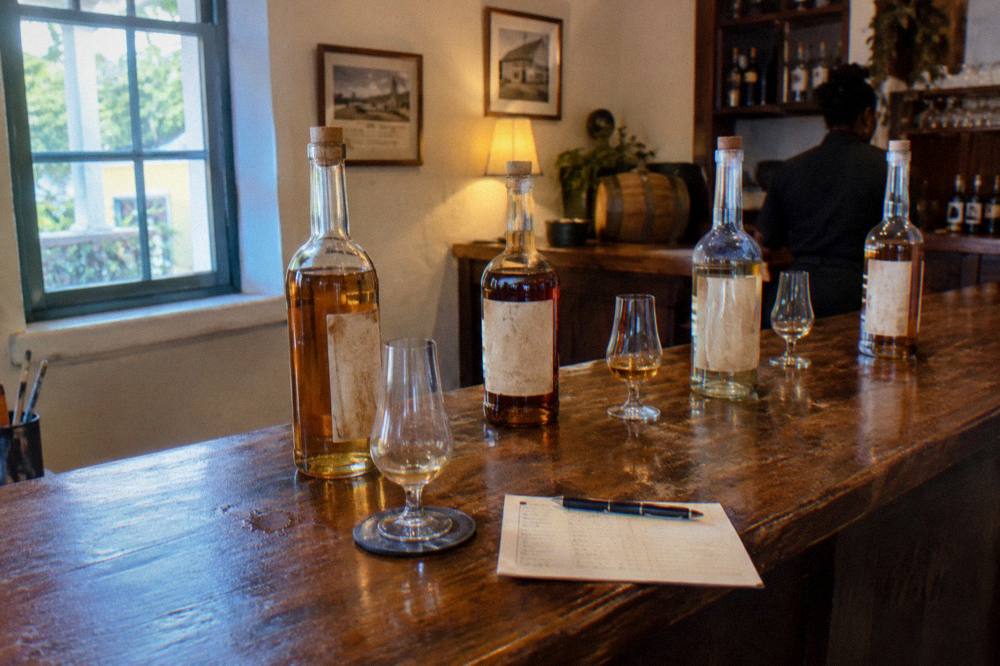 Rum bottles and tasting glasses arranged on a wooden bar counter