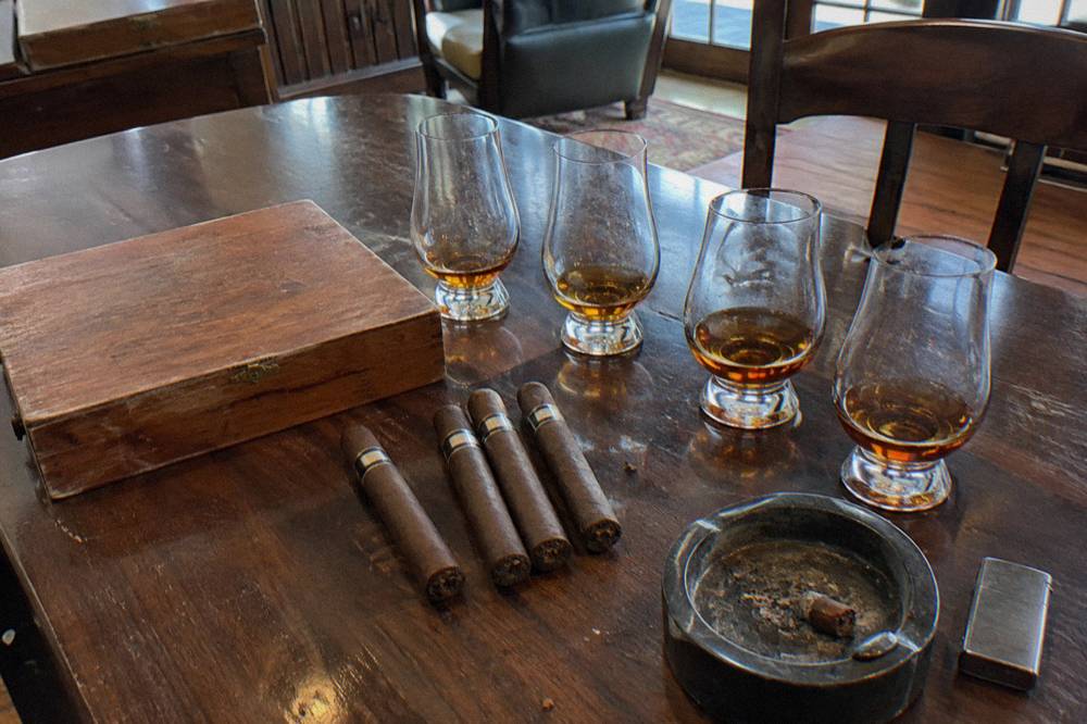 A tasting room table set with rum glasses and an open cigar box
