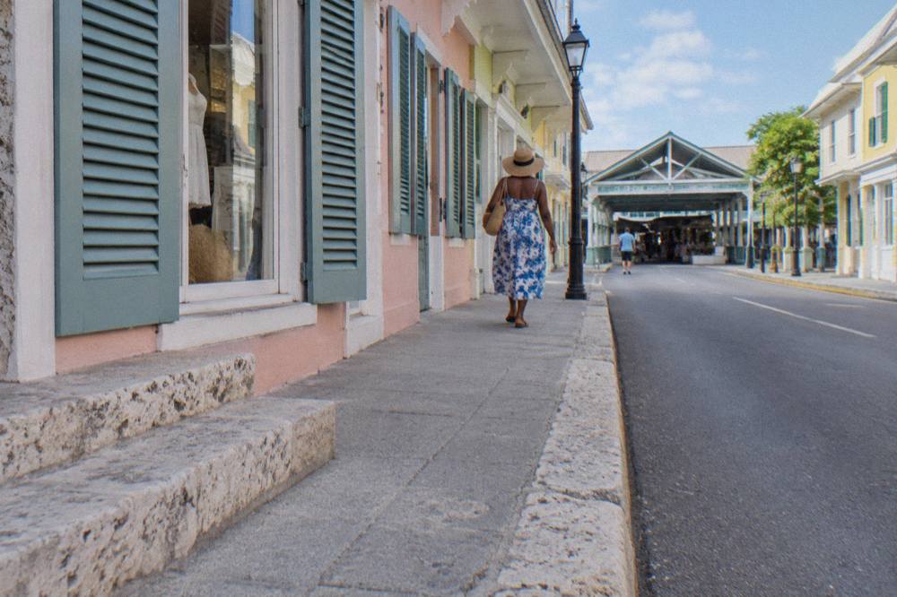 Passengers walking along Bay Street past colorful colonial buildings in downtown Nassau