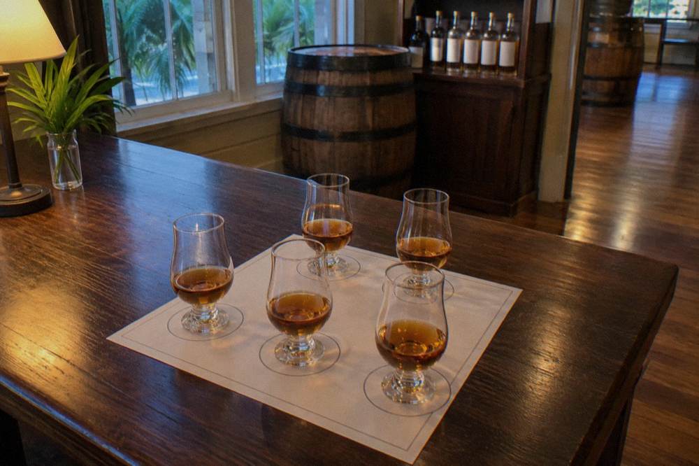 Glasses of amber rum lined up on a wooden tasting bar