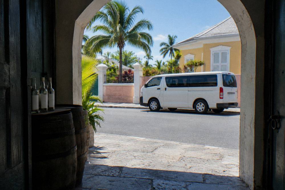 A tour van parked on a Nassau street beside pastel colonial buildings