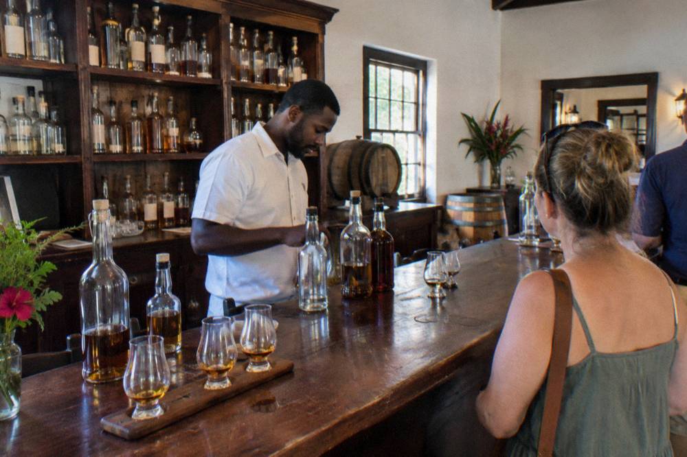 A guide pouring rum behind a wooden bar in a distillery tavern