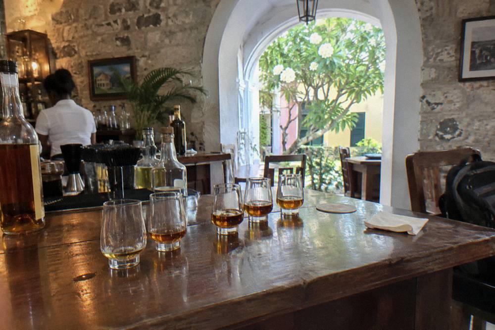 A row of rum tasting glasses arranged on a wooden bar top