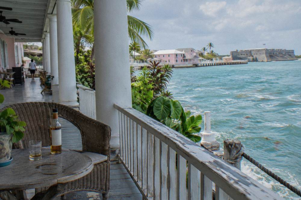 Wooden porch of a historic estate building with white columns and palm trees