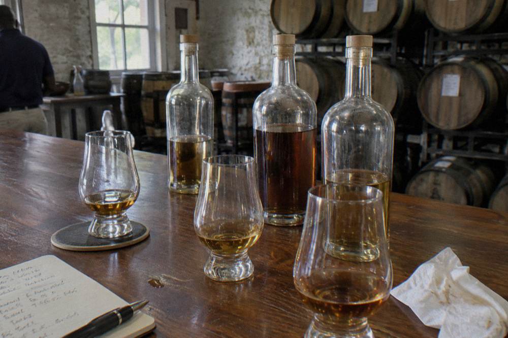 Rum bottles and small tasting glasses set out on a distillery tasting table