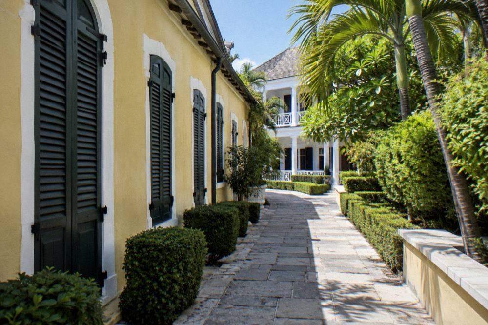Historic Nassau estate building surrounded by palm trees under a clear sky