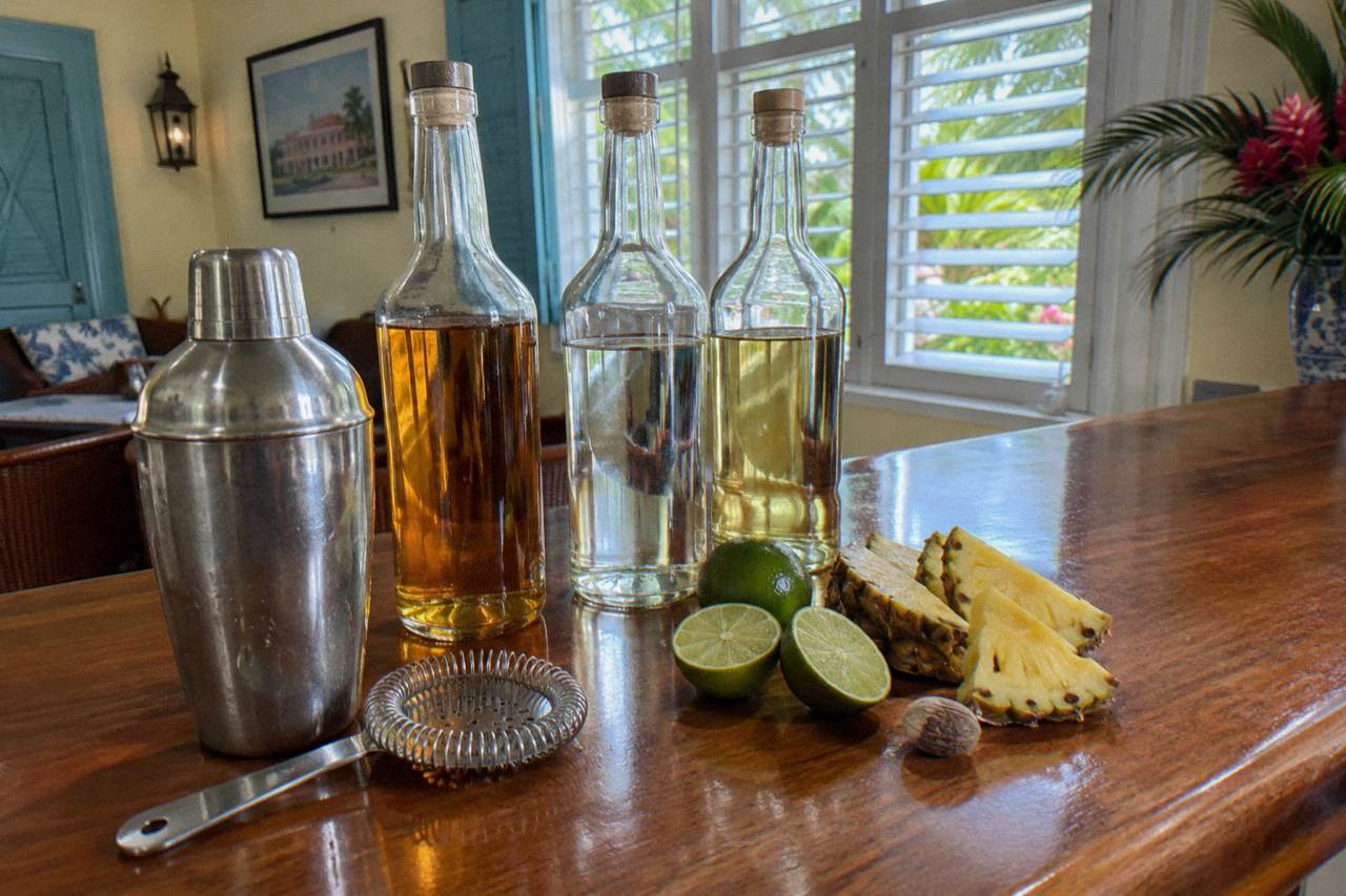 Cocktail shakers, rum bottles and fresh fruit arranged on a wooden bar counter