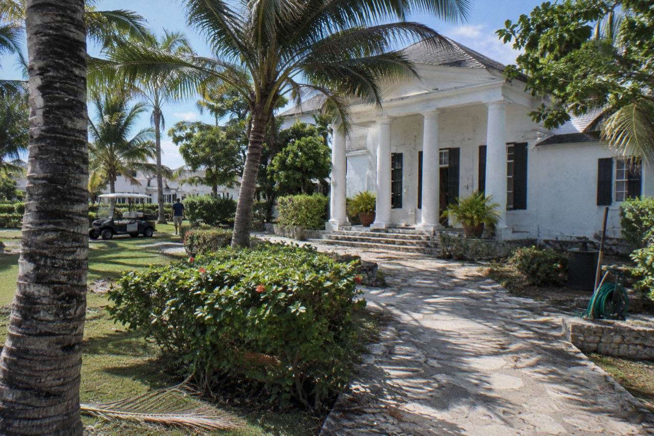 Historic stone distillery building with white columns and palm trees on a sunny afternoon in Nassau