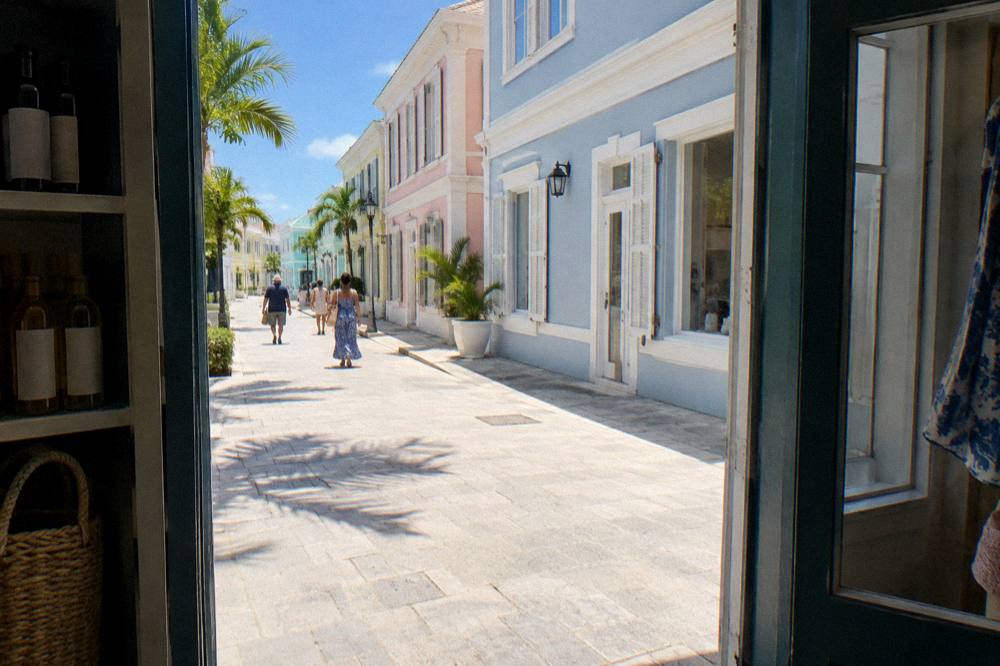 Sunny Nassau street with shops and a cruise ship visible across the harbor