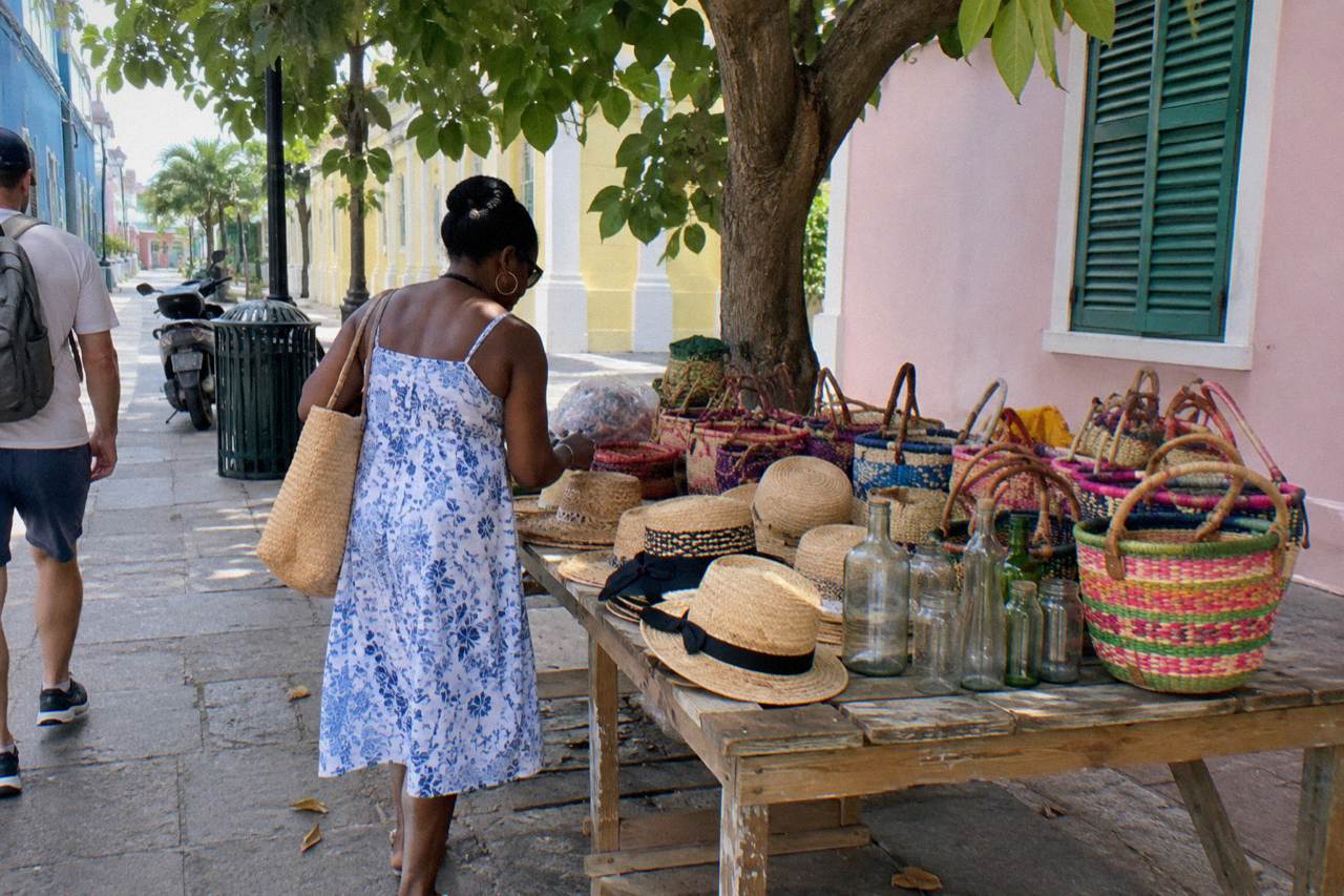 Wooden craft stalls with woven straw hats and bags in a bright open-air market hall