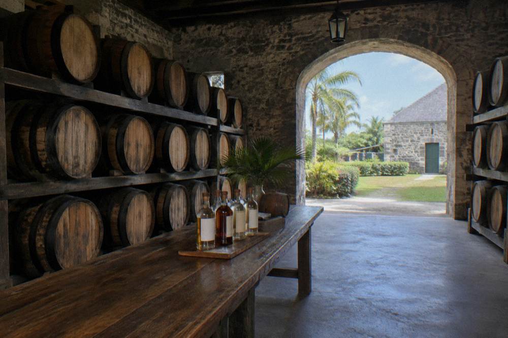 Rows of white oak rum barrels in a dimly lit estate storehouse