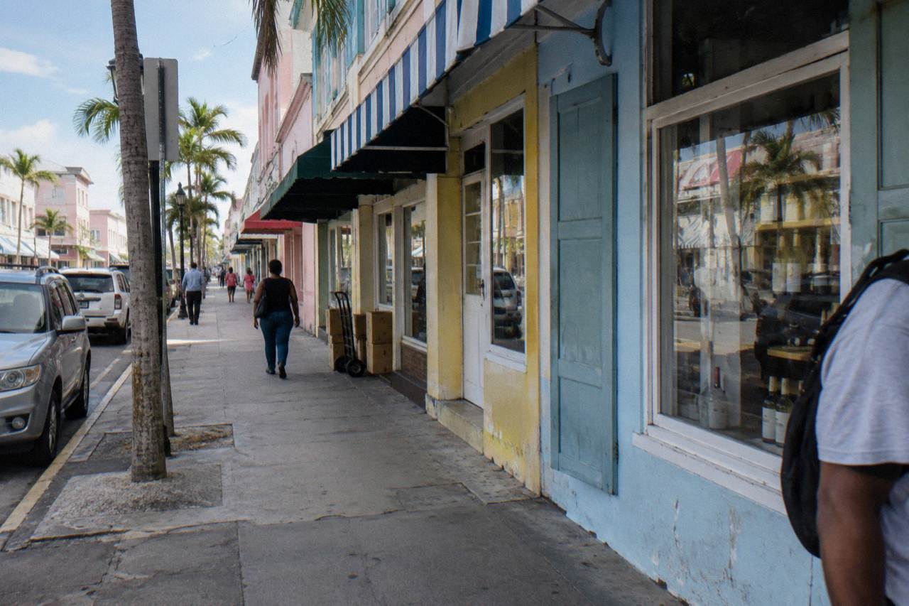 A tree-lined street of pastel colonial buildings rising gently uphill from a Nassau waterfront