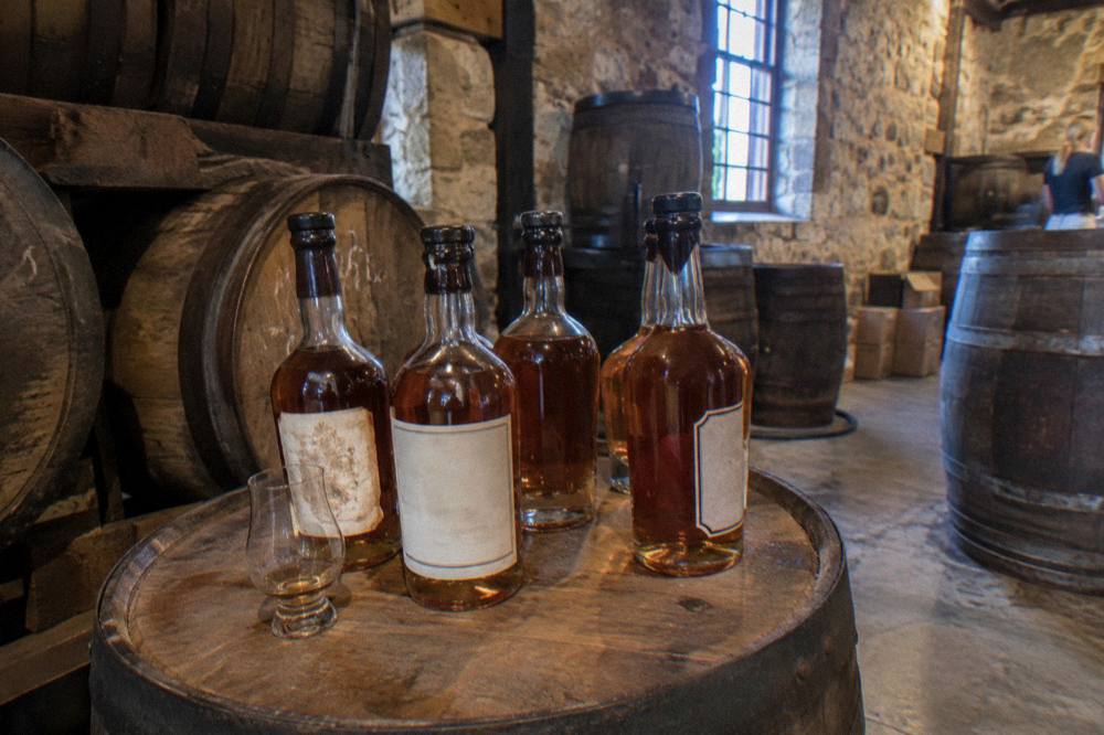 Amber rum bottles and wax seals arranged on a wooden barrel top in a distillery