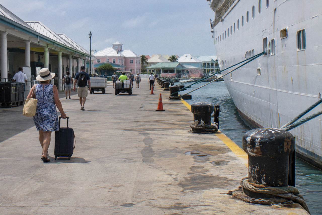 Cruise ships docked at a waterfront terminal with pastel colonial buildings along the shore